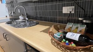 Keittiössä on ruostumattomasta teräksestä valmistettu pesuallas, mikroaaltouuni sekä kori, jossa on leipää, pullo ja joitain pakattuja elintarvikkeita.