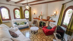 Una sala de estar acogedora con chimenea, un sofá, un sillón rojo y un televisor.