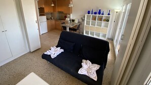 Un espacio habitable compacto con kitchenette, comedor y sofá con almohadones decorativos.