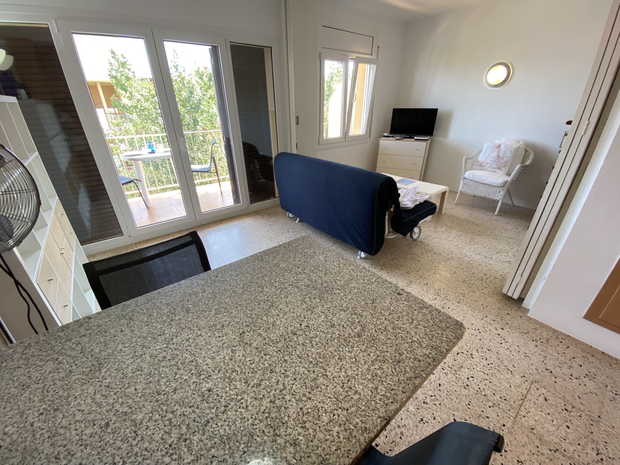 A compact living space with a kitchenette, a dining area, and a seating area with a sofa and a chair.