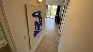 Un pasillo con una lámpara, una obra enmarcada y vista a una habitación con balcón.