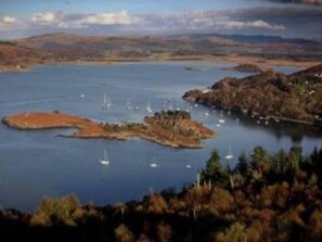 A coastal landscape with a large body of water, several small islands, and sailboats. - Crinan Canal Cottage No8, Kilmartin (Lochgilphead)