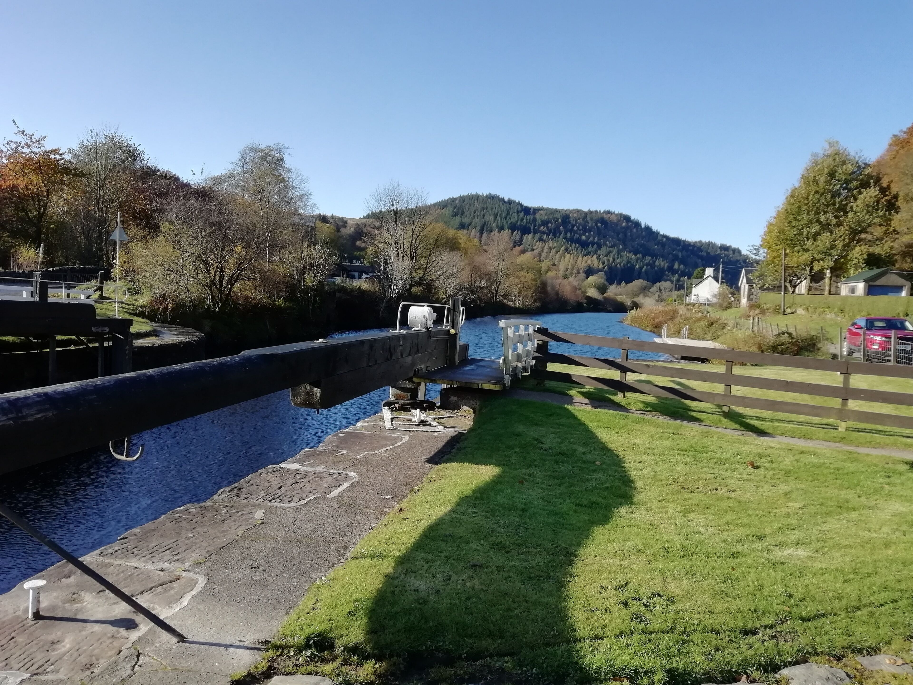 En sluse på en flod med en græsplæne og en bakke i baggrunden.