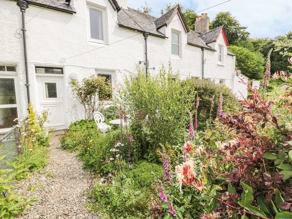 A white house with a garden path leading to a white chair and a table. - Crinan Canal Cottage No8, Kilmartin (Lochgilphead)