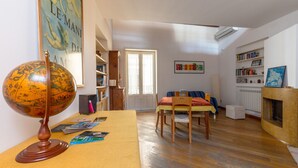 Una sala de estar acogedora con un globo de madera sobre una mesa, una estantería, una chimenea y un comedor con una mesa y sillas.