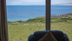 A view from a window overlooking a grassy field with sheep and a house in the distance. - Cottage 259 - Renvyle - sleeps 6 guests  in 3 bedrooms (Renvyle)