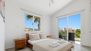 A bedroom with a bed, nightstands, a window, and a balcony. - Villa Roker by Ezoria Villas (Coral Bay)
