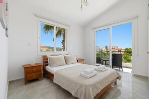 Une chambre à coucher avec un lit, des tables de chevet, une fenêtre et un balcon.