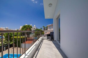 Ein Balkon mit Pool, Blick auf Nachgebäuden und einem klaren Himmel.