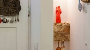 A room with a stone fireplace, a red statue, and a copper lamp. - JOIVY Calm 1-bed flat (Lisbon)