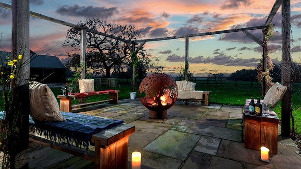 An outdoor seating area with a fire feature, wooden furniture, and a view of the sunset. - Cart House 2 bedrooms - sleeps 4-5 guests  in 2 bedrooms (Beverley)
