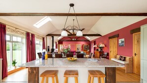 A spacious kitchen with a large island, wooden stools, and a dining area with a red wall and wooden beams. - Cart House 2 bedrooms - sleeps 4-5 guests  in 2 bedrooms (Beverley)