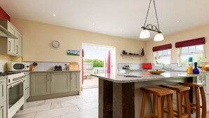 A modern kitchen with a central island, wooden stools, and a view to the outside. - Cart House 2 bedrooms - sleeps 4-5 guests  in 2 bedrooms (Beverley)