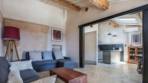 A modern living room with a sofa, coffee table, and lamp. There is a kitchen area visible through an open doorway. - Belle Arti' Stunning Apartment (Florence)