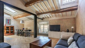 A spacious living area with a herringbone floor, a dark sofa, a wooden coffee table, and a television on a cabinet. - Belle Arti' Stunning Apartment (Florence)