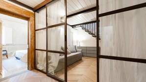 A modern interior with a wooden floor, a grey sofa, and a staircase. - Belle Arti' Stunning Apartment (Florence)