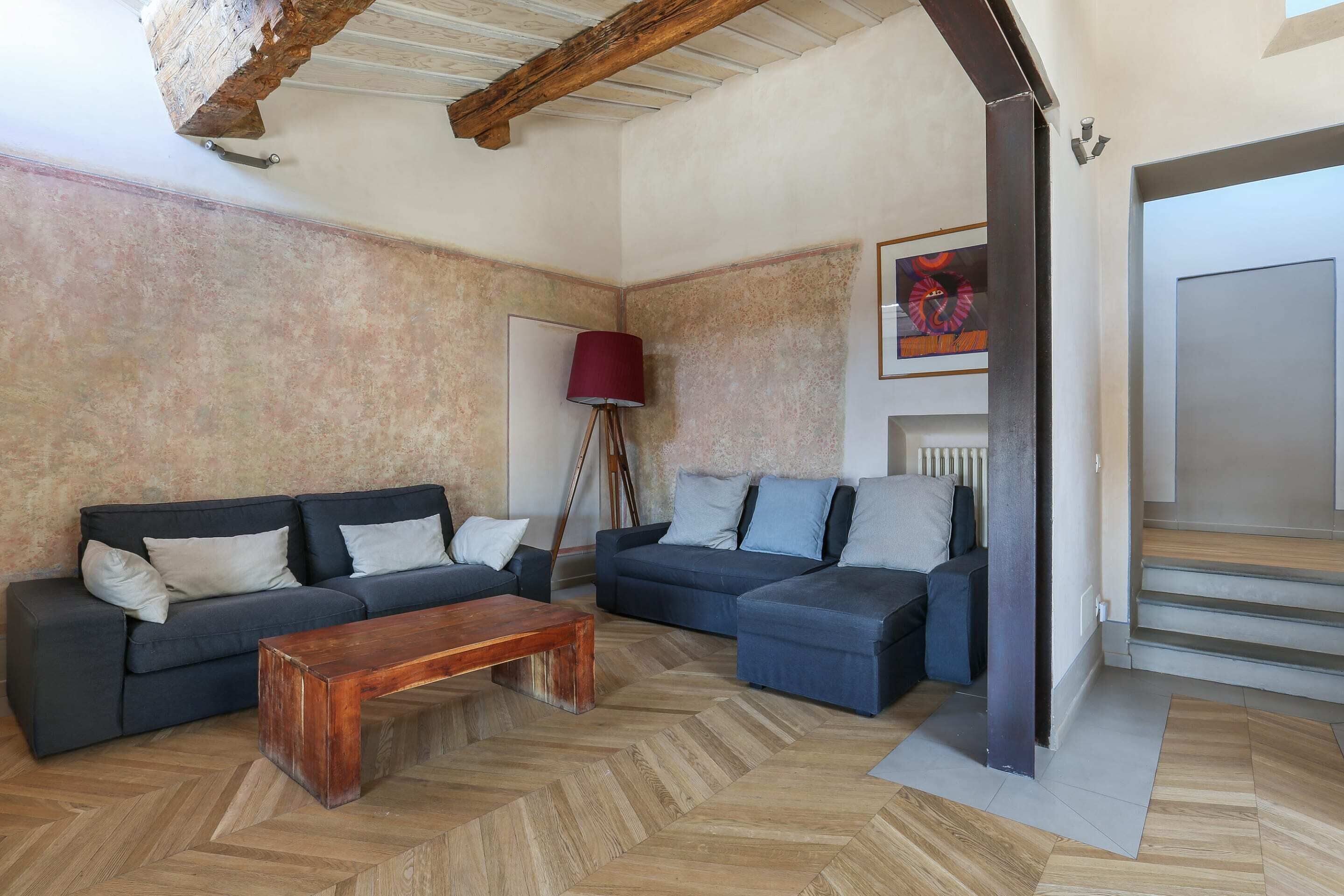 A living room with two dark sofas, a wooden coffee table, and a herringbone floor.