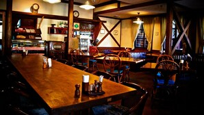 A cozy restaurant with wooden tables and chairs, a bar area, and a clock on the wall. - Spa Lodge Redwood Inn (Takayama)