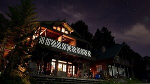 A two-story building with a balcony, illuminated windows, and a sign that reads "Redwood Inn." - Spa Lodge Redwood Inn (Takayama)