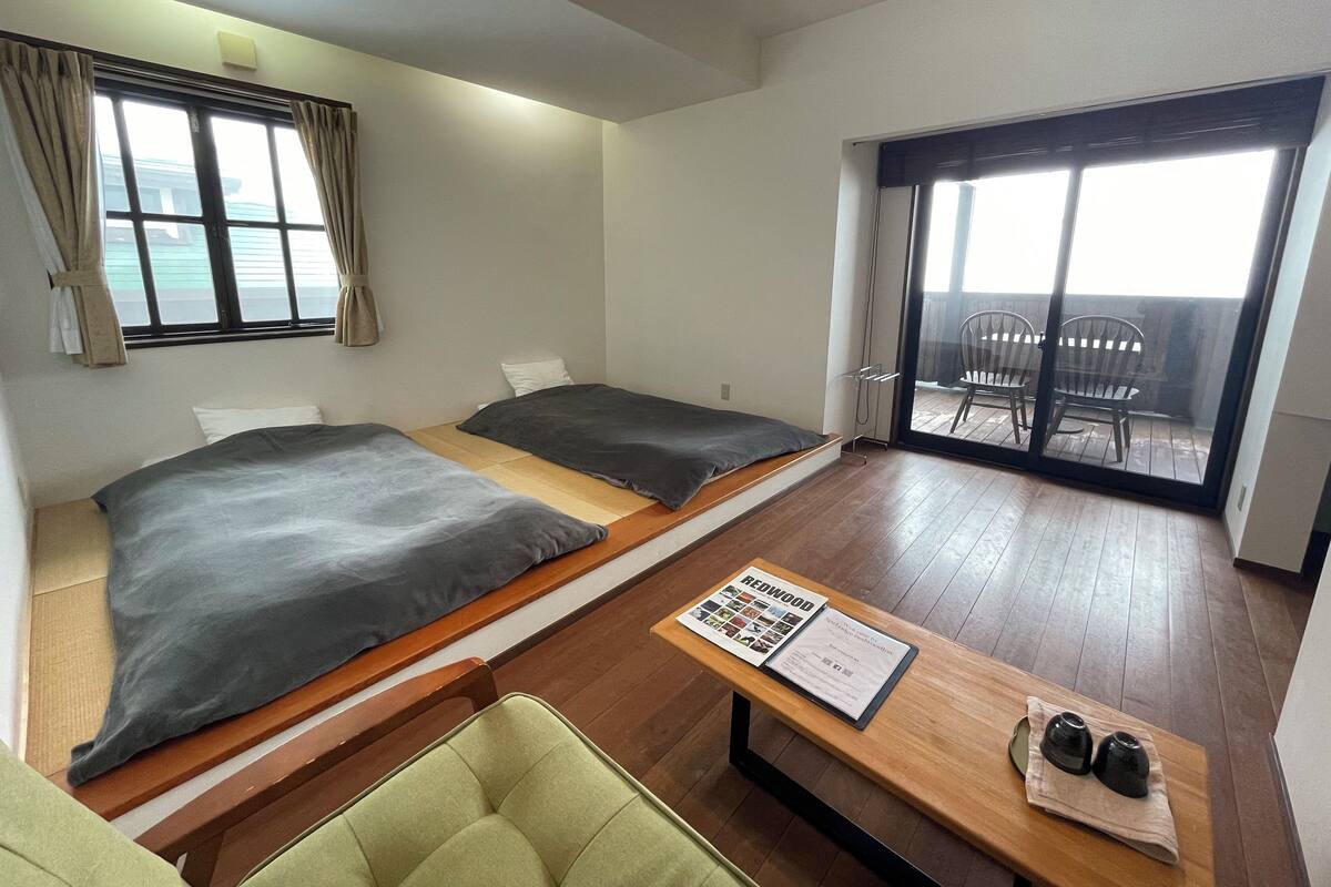 A room with two beds, a table with a menu, and a view of the outside balcony.