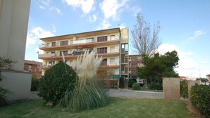 A multi-story residential building with balconies, a well-maintained lawn, and a clear sky. - Mare Nostrum 2D 324 - Close to the beach, modern (Torroella de Montgri)