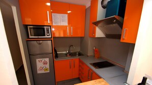 A compact kitchen with orange cabinets, a stainless steel sink, a microwave, and a wooden countertop. - Mare Nostrum 2D 324 - Close to the beach, modern (Torroella de Montgri)