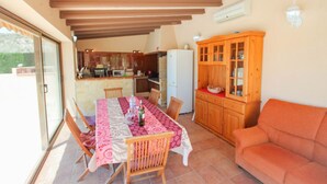 A dining area with a table set for four, wooden chairs, a wooden cabinet with glass doors, and a sofa. - Santa Ana - pretty holiday property with garden and private pool in Benissa (Benissa)