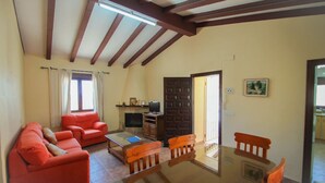 A living room with a sofa, a glass-top table, and wooden chairs. There is a television on a stand and a door leading to another room. - Santa Ana - pretty holiday property with garden and private pool in Benissa (Benissa)