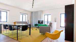 Una sala de estar moderna con comedor, televisor de pantalla plana y un ventanal grande.
