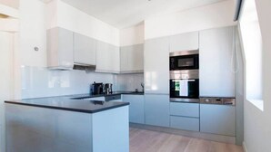 Una cocina moderna con una isla central, electrodomésticos de acero inoxidable y armarios de tonos claros.
