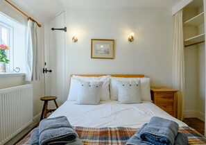 Cozy retreat with a neatly made bed, framed artwork, and a comfortable nightstand.