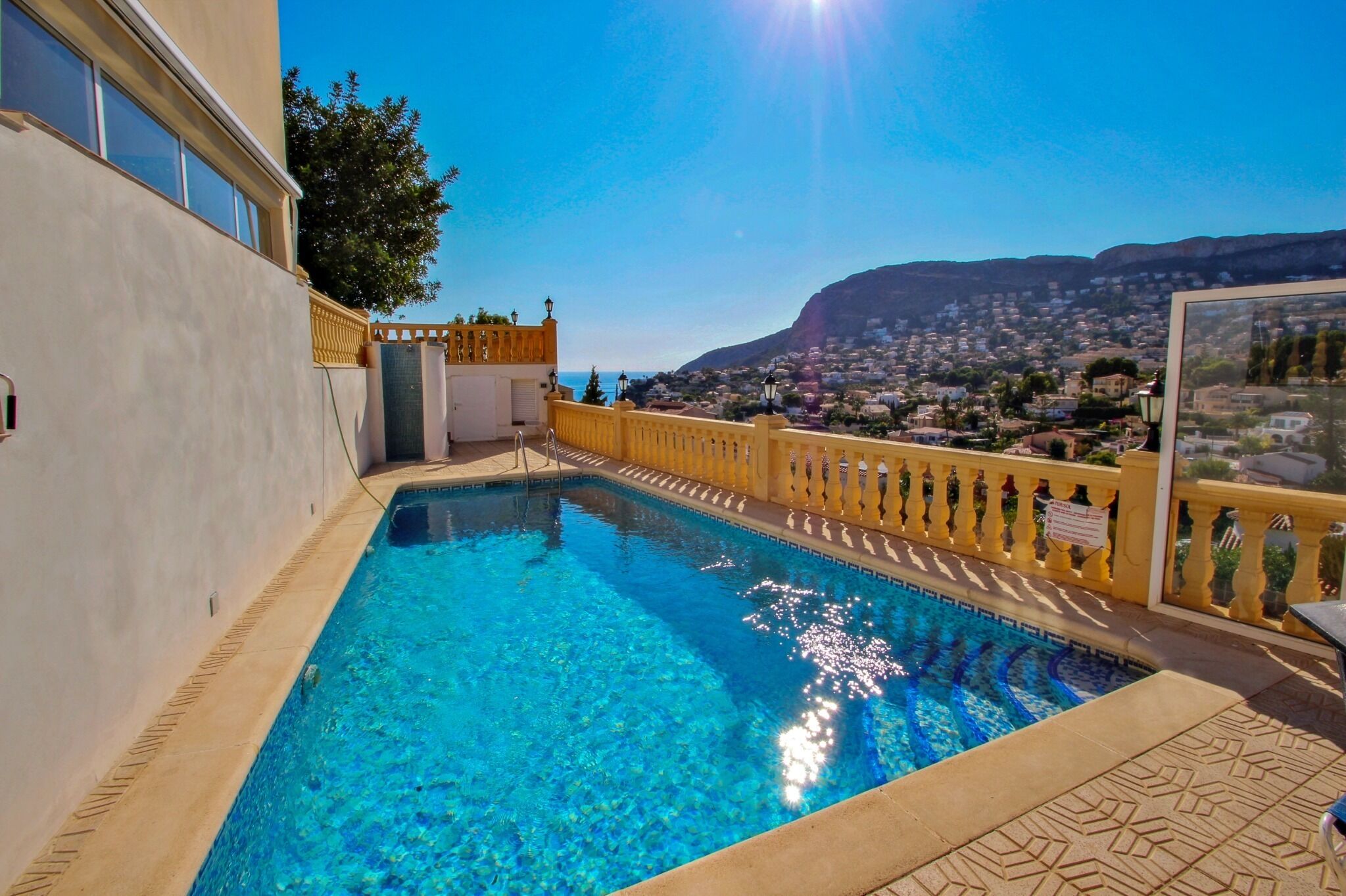 A swimming pool with a view of a town and mountains in the background.