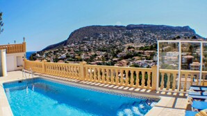 Una piscina amb vista a una població de muntanya al fons.