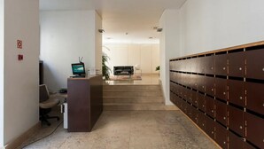 Un ufficio moderno con reception, computer e zona salotto. Una scala conduce a un deposito con armadietti.