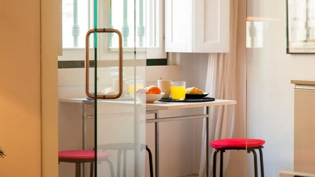 Una cucina con un tavolo apparecchiato per la colazione, con succo d'arancia e croissant.