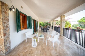 A covered patio with stone walls, green shutters, and outdoor furniture. - Villa Contrada  - Holiday Rental by the Sea with swimming pool in Scopello, Sicily (Scopello)