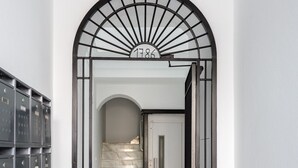 A hallway with a black metal gate, a marble staircase, and a checkered floor pattern.