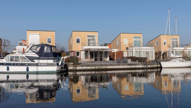 Marina con casas modernas, un barco amarrado y cielo despejado.