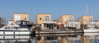 Lyx fritidshus med full härdad terrass vid vattnet. Den långa utomhusbordet under terrassen