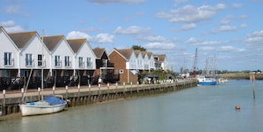 A waterfront property with a row of white houses, a dock with boats, and a pier extending into the water.