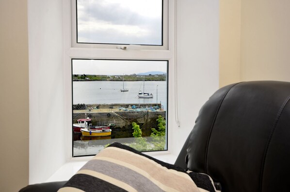 A view from a window overlooking a harbor with boats and a small hill in the distance.