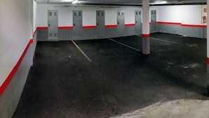 Un estacionamiento con pisos de concreto, paredes blancas y detalles en rojo.