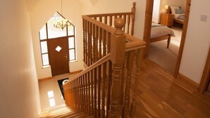 Eine Holztreppe führt zu einem Schlafzimmer mit einem Bett und einem Nachttisch.