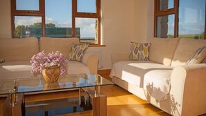 Ein Wohnzimmer mit zwei Sofas, einem Glastisch und einer Blumenvase.