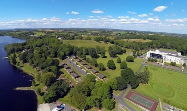 A large estate with a lake, green fields, and a tennis court.