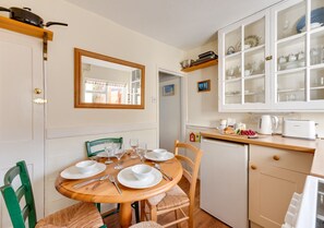 Cozy kitchen with a round dining table for four, equipped with a dishwasher and refrigerator.