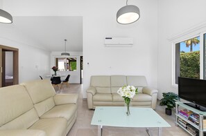 Un salon moderne avec un canapé, une table basse, un téléviseur et une bibliothèque.