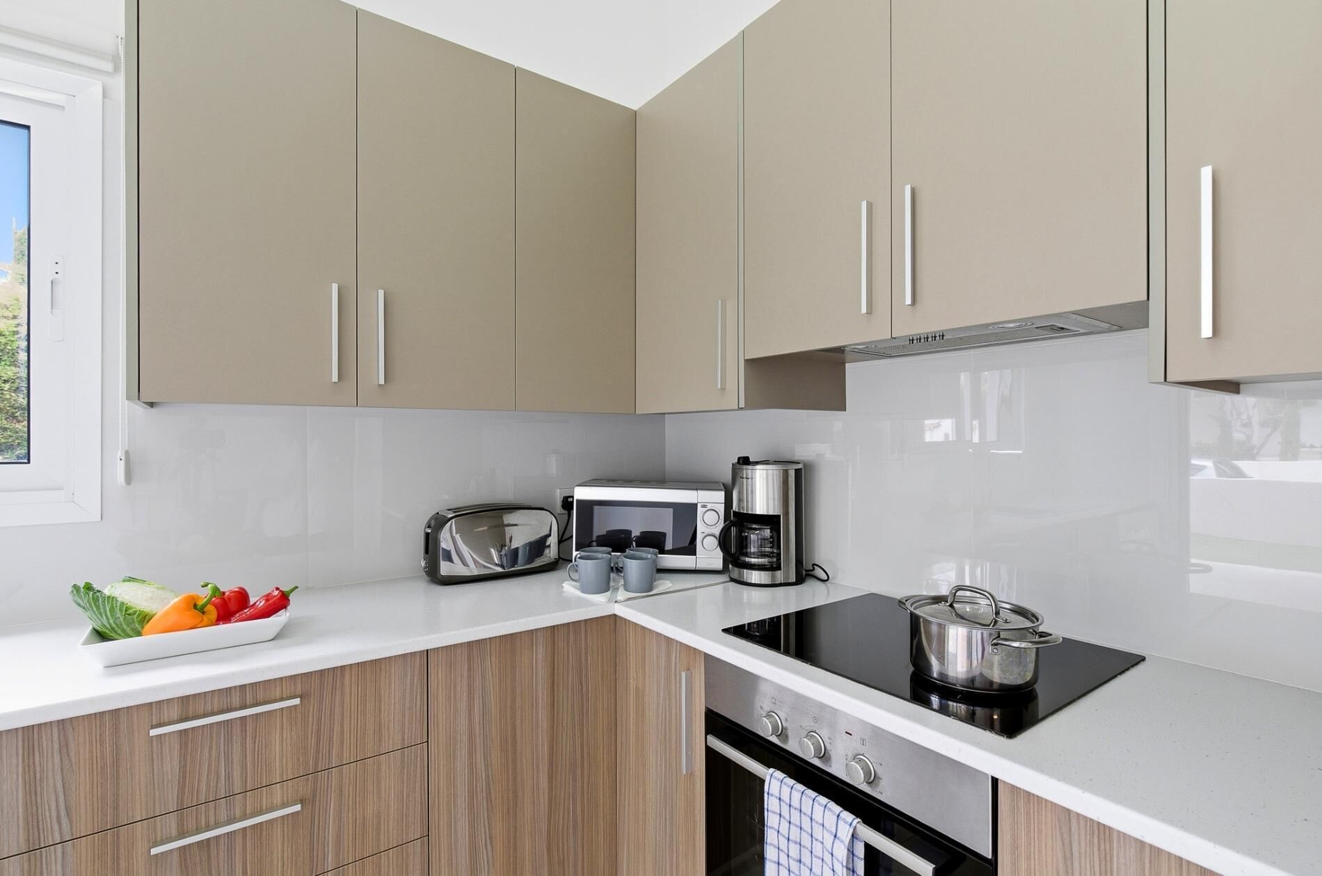 A modern kitchen with wooden cabinets, a built-in stove, a microwave, and a coffee maker.