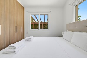 Une chambre à coucher avec un lit, une fenêtre, une armoire en bois et une vue sur la verdure.