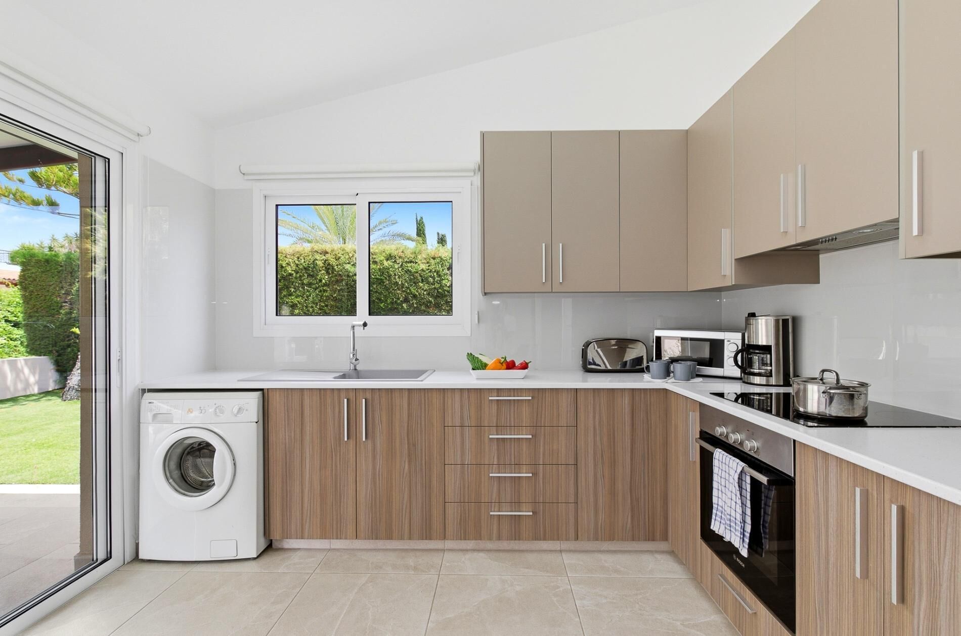 Une cuisine moderne équipée d’un lave-linge, d’un four à micro-ondes et d’un four traditionnel.
